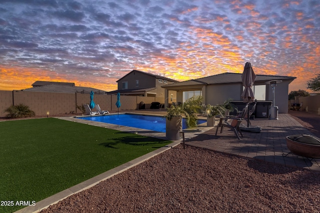 pool at dusk with a lawn and a patio area