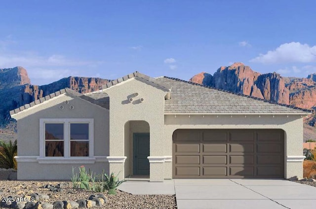 view of front of home with an attached garage, a mountain view, concrete driveway, and stucco siding