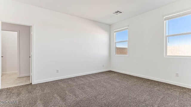 carpeted spare room with visible vents and baseboards