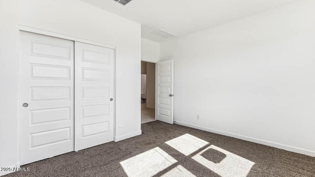 unfurnished bedroom with dark colored carpet, a closet, and baseboards