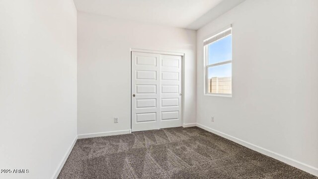 empty room featuring dark carpet and baseboards