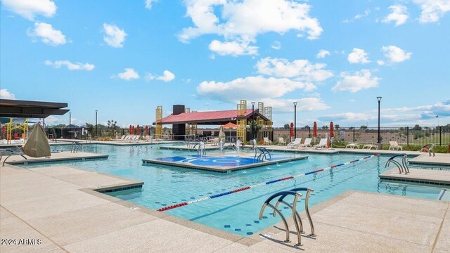 community pool featuring a patio, fence, and a hot tub