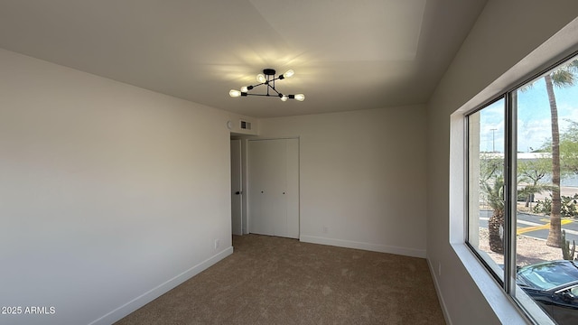 spare room with plenty of natural light, a chandelier, baseboards, and carpet