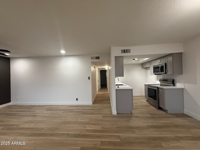 kitchen featuring appliances with stainless steel finishes, gray cabinetry, light wood finished floors, and recessed lighting