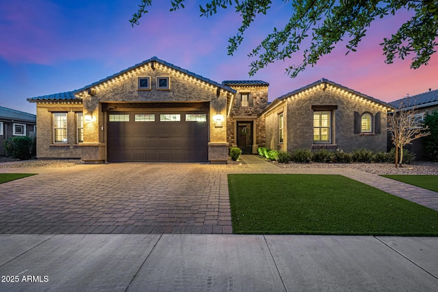 view of front facade with a tile roof, a garage, decorative driveway, and stucco siding