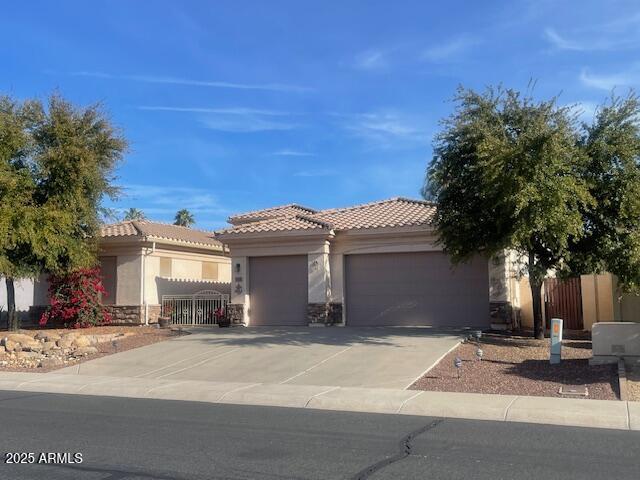 view of front of home with a tiled roof, an attached garage, driveway, and fence