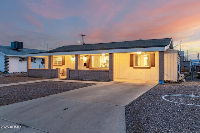 ranch-style home featuring cooling unit and brick siding