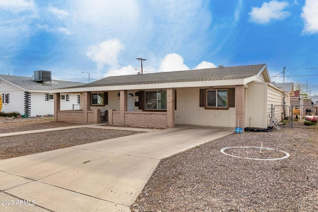 ranch-style home featuring cooling unit, covered porch, and brick siding