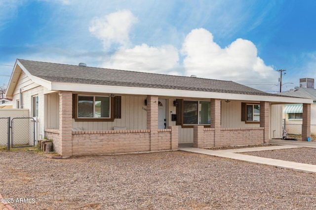 ranch-style home with a gate, a porch, brick siding, a shingled roof, and board and batten siding