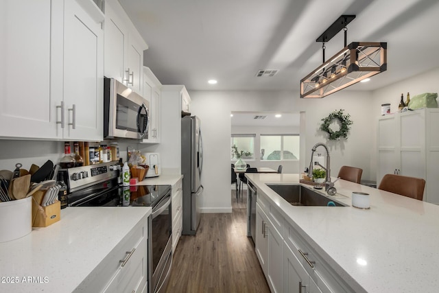 kitchen with light stone counters, visible vents, dark wood finished floors, a sink, and stainless steel appliances