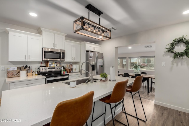 kitchen with visible vents, a sink, stainless steel appliances, light countertops, and white cabinets