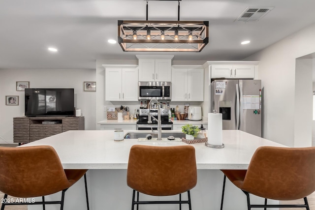 kitchen featuring visible vents, appliances with stainless steel finishes, white cabinetry, and light countertops