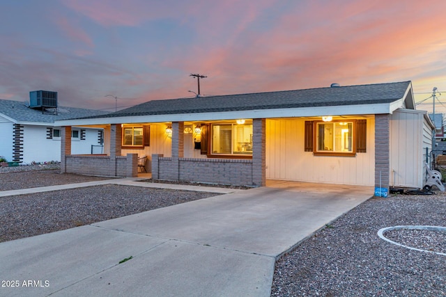 ranch-style house with central AC unit, covered porch, and roof with shingles