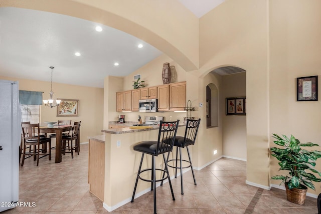 kitchen with a kitchen bar, white appliances, light brown cabinets, decorative light fixtures, and an inviting chandelier