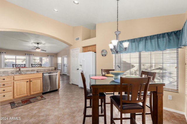 tiled dining area with ceiling fan with notable chandelier, vaulted ceiling, and sink