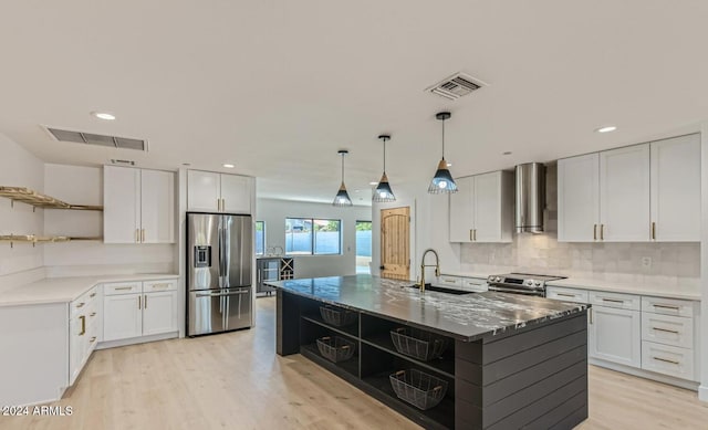 kitchen with white cabinets, sink, wall chimney range hood, and stainless steel appliances