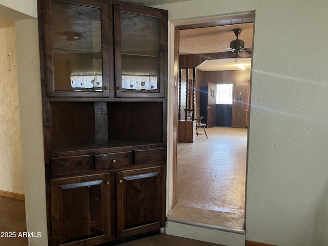 hallway featuring wooden walls, arched walkways, a textured wall, and a textured ceiling