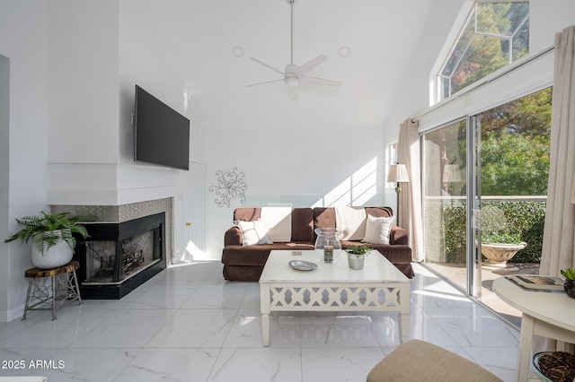 living room featuring a towering ceiling, a fireplace, and ceiling fan