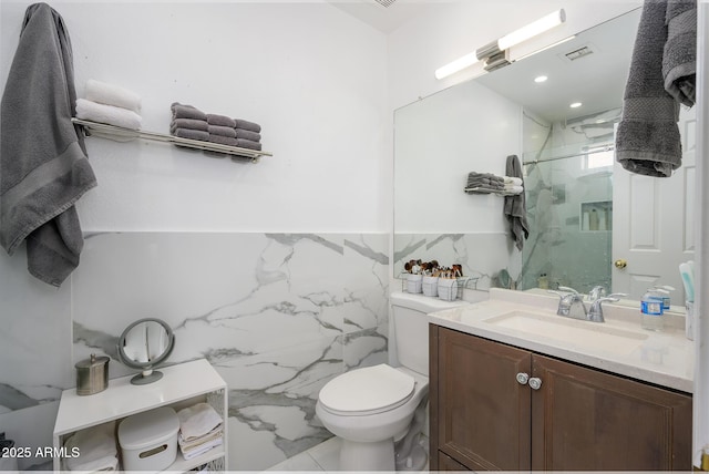 bathroom with vanity, toilet, a shower with shower door, and tile walls