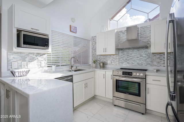 kitchen featuring white cabinetry, stainless steel appliances, and wall chimney range hood