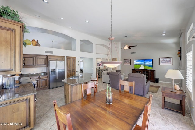 dining space featuring sink, light tile patterned floors, high vaulted ceiling, and ceiling fan