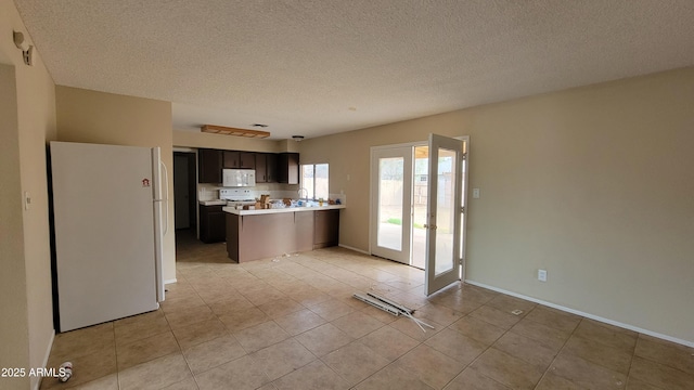 kitchen with white appliances, dark brown cabinets, kitchen peninsula, and a textured ceiling