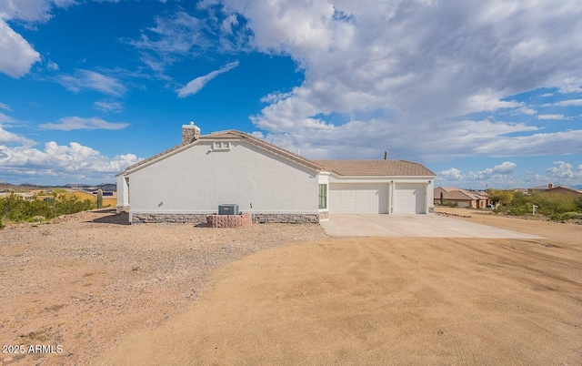 26215 N 115th Ave, Peoria, AZ 85383 - view of property exterior with an attached garage, driveway, a chimney, stucco siding, and cooling unit