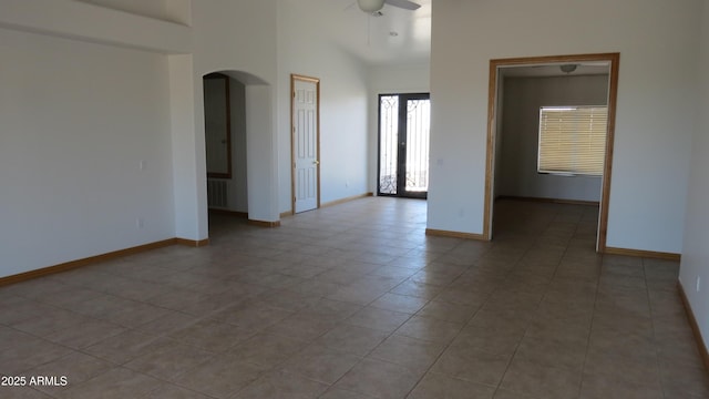 26215 N 115th Ave, Peoria, AZ 85383 - tiled empty room featuring arched walkways, baseboards, a ceiling fan, and a high ceiling