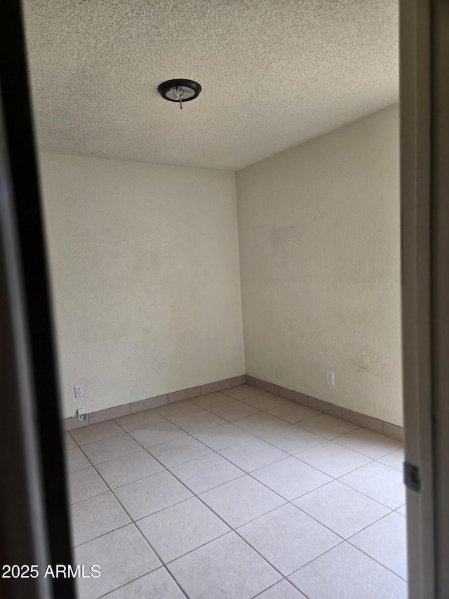unfurnished room featuring a textured ceiling and light tile patterned floors