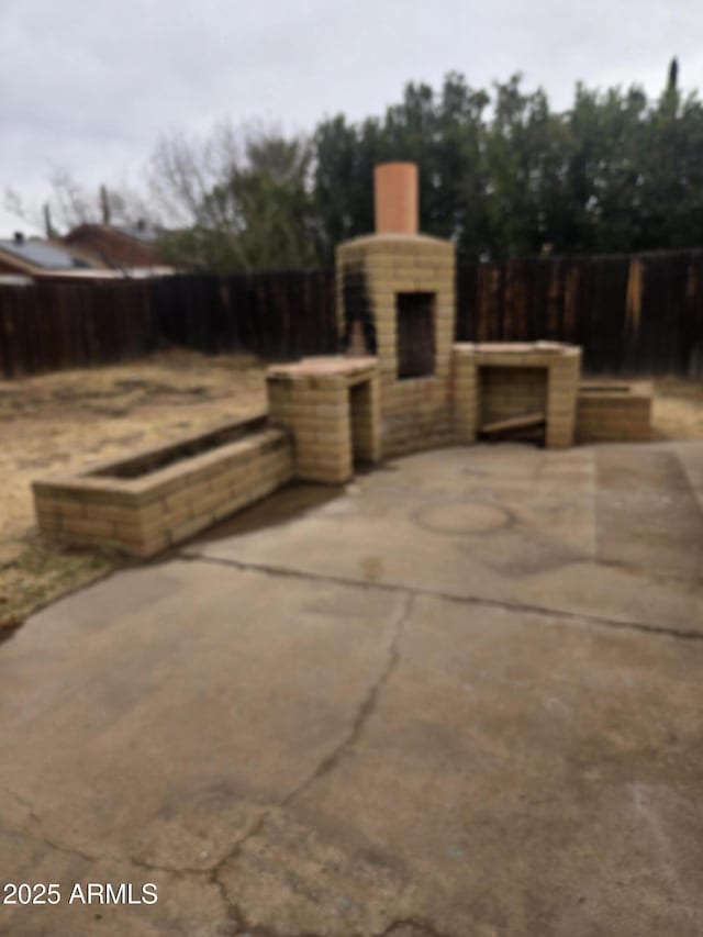 view of patio with a fireplace and fence