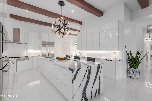 kitchen with beam ceiling, backsplash, a kitchen island, and wall chimney range hood