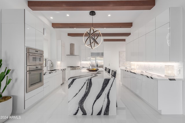 kitchen with beam ceiling, backsplash, pendant lighting, and wall chimney range hood