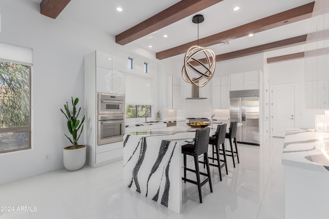 kitchen with light stone countertops, stainless steel appliances, beam ceiling, white cabinets, and hanging light fixtures