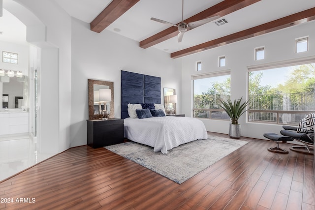 bedroom featuring beam ceiling, ceiling fan, a towering ceiling, and wood-type flooring