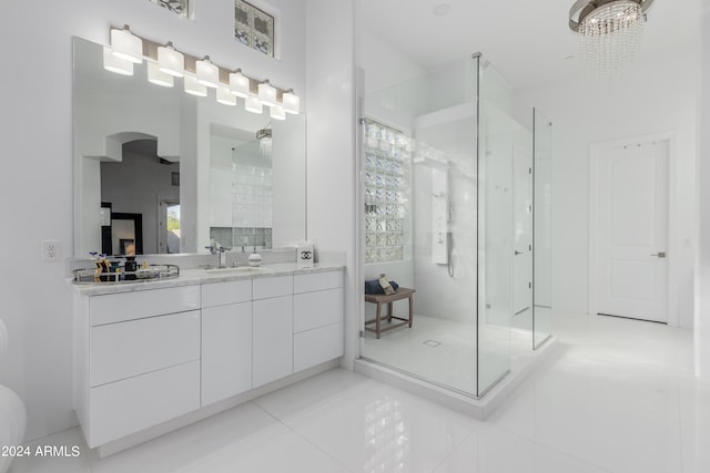 bathroom featuring tile patterned flooring, a tile shower, vanity, and an inviting chandelier