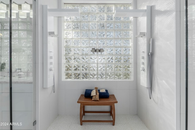 bathroom with a shower with door and tile walls