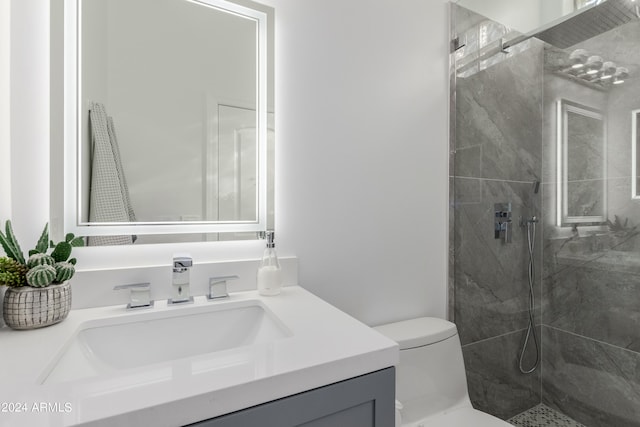 bathroom featuring a tile shower, vanity, and toilet