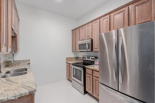 kitchen with light stone countertops, sink, and stainless steel appliances