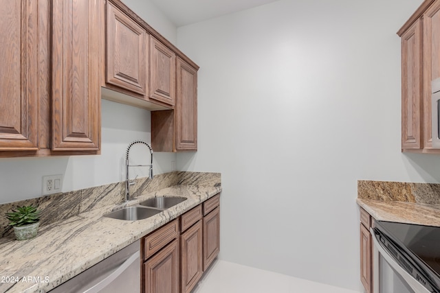 kitchen featuring light stone countertops, stainless steel range, and sink