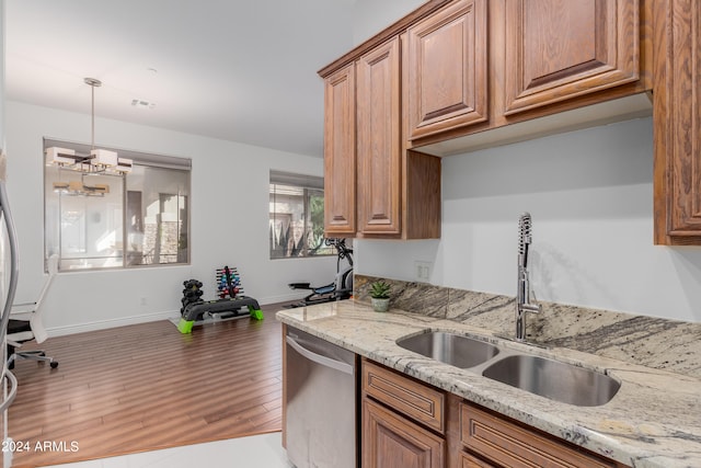 kitchen with light stone countertops, stainless steel dishwasher, sink, a notable chandelier, and hardwood / wood-style floors