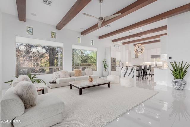 living room with ceiling fan with notable chandelier, beam ceiling, and sink