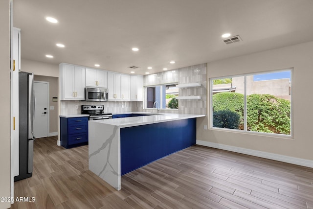 4913 E Acoma Dr, Scottsdale, AZ 85254 - kitchen with appliances with stainless steel finishes, a peninsula, a sink, blue cabinets, and decorative backsplash