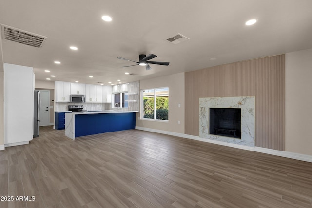 4913 E Acoma Dr, Scottsdale, AZ 85254 - unfurnished living room with ceiling fan, recessed lighting, baseboards, a high end fireplace, and light wood finished floors