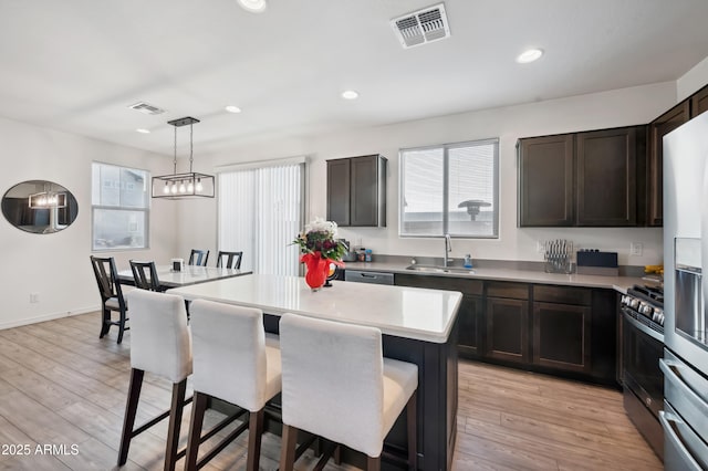 kitchen with light hardwood / wood-style floors, a center island, sink, and hanging light fixtures