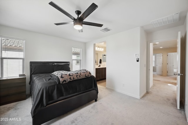 bedroom with ceiling fan, light colored carpet, and ensuite bath