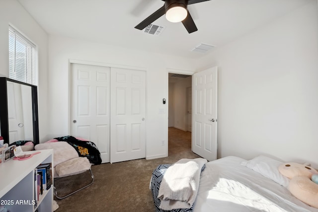 bedroom with ceiling fan, dark carpet, and a closet