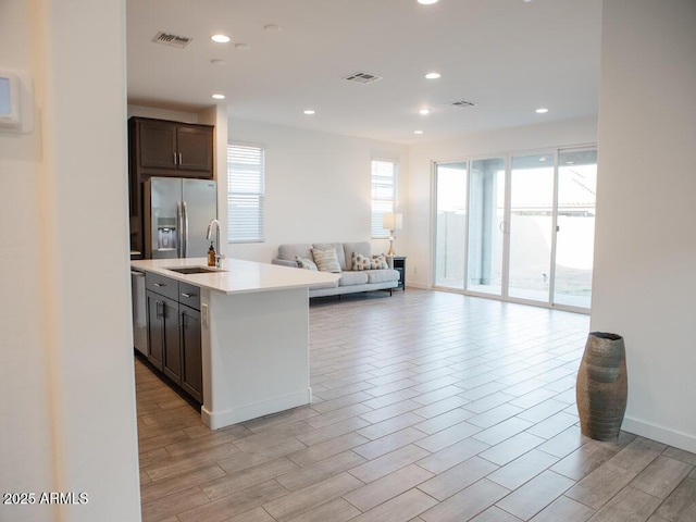 kitchen featuring visible vents, open floor plan, light countertops, appliances with stainless steel finishes, and an island with sink