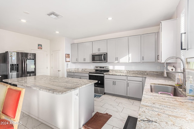 kitchen featuring a kitchen bar, light stone countertops, sink, and stainless steel appliances