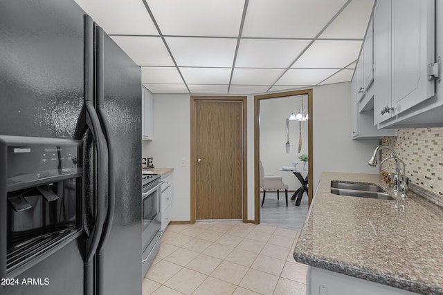 kitchen with black refrigerator with ice dispenser, white cabinets, sink, tasteful backsplash, and light tile patterned flooring