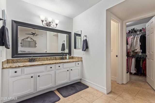 bathroom with a sink, a spacious closet, tile patterned flooring, baseboards, and double vanity